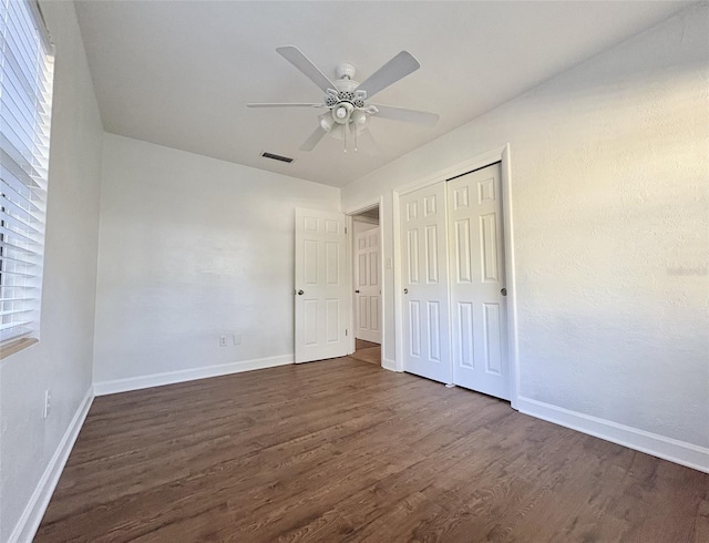 unfurnished bedroom with visible vents, baseboards, ceiling fan, dark wood-type flooring, and a closet