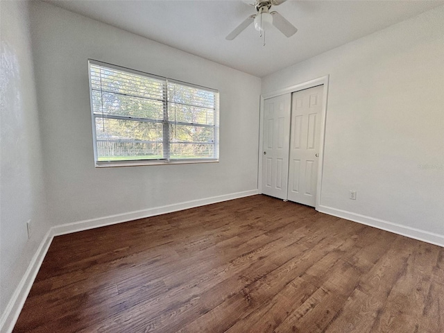 unfurnished bedroom with dark wood finished floors, ceiling fan, a closet, and baseboards