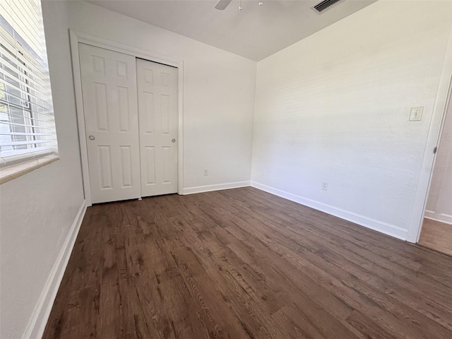 unfurnished bedroom featuring visible vents, baseboards, dark wood finished floors, a closet, and a ceiling fan