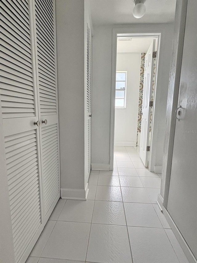 hallway with light tile patterned floors and baseboards