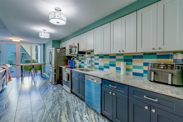 kitchen featuring decorative backsplash, stainless steel appliances, marble finish floor, white cabinetry, and a sink