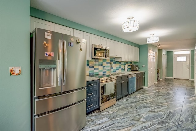 kitchen featuring a sink, tasteful backsplash, appliances with stainless steel finishes, white cabinets, and light countertops