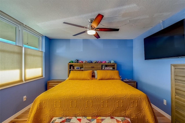 bedroom with baseboards, a textured ceiling, and wood finished floors