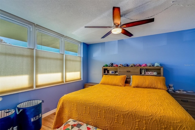 bedroom featuring ceiling fan, baseboards, a textured ceiling, and wood finished floors