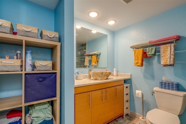 bathroom with baseboards, toilet, vanity, and walk in shower