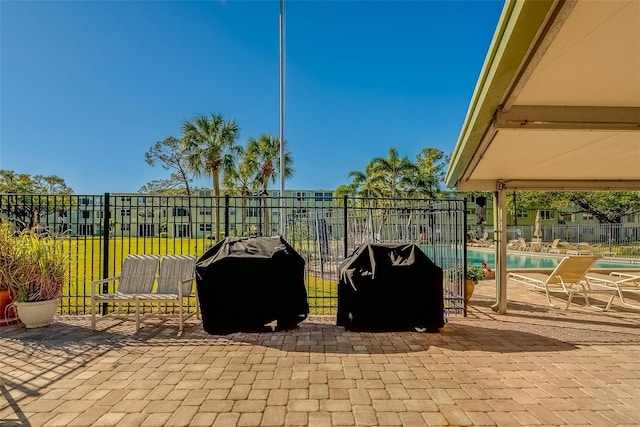 view of patio with grilling area, a community pool, and fence