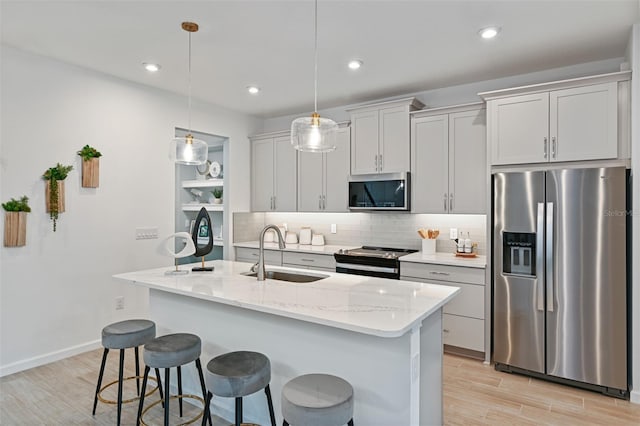 kitchen with a sink, stainless steel appliances, a kitchen breakfast bar, tasteful backsplash, and light wood-type flooring