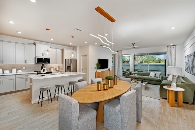 dining room with light wood finished floors, visible vents, recessed lighting, and a ceiling fan