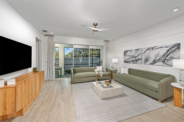 living area with visible vents, a textured ceiling, light wood-type flooring, and ceiling fan