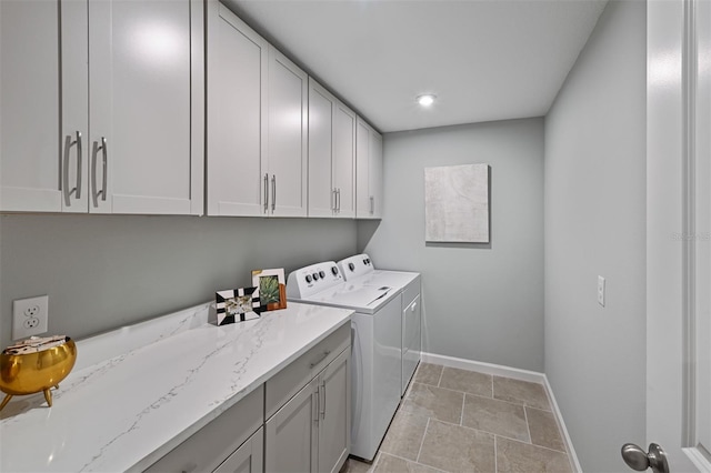 clothes washing area featuring baseboards, cabinet space, and independent washer and dryer