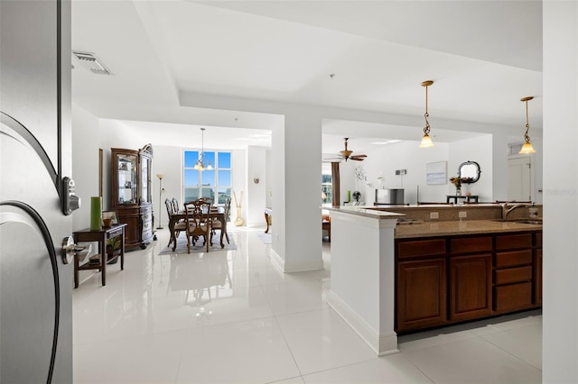 kitchen featuring visible vents, decorative light fixtures, a sink, light tile patterned floors, and baseboards