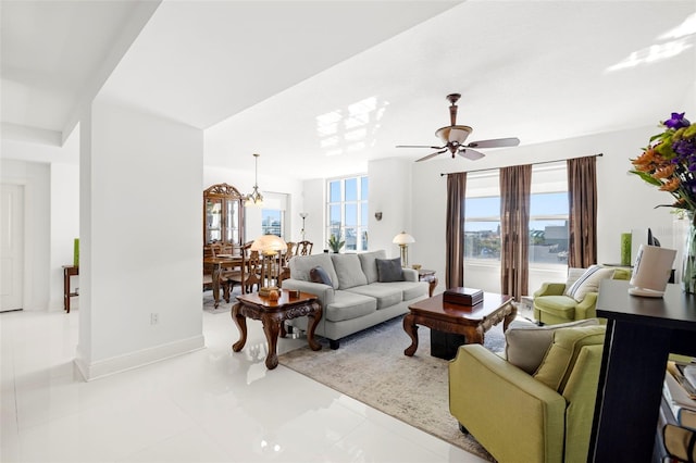 living room with baseboards and ceiling fan with notable chandelier