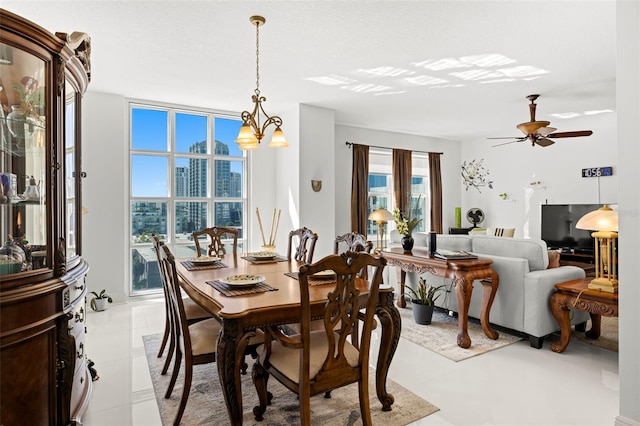 dining area with a wall of windows and ceiling fan with notable chandelier