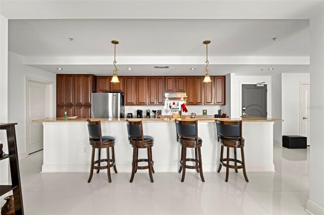 kitchen featuring recessed lighting, a kitchen breakfast bar, pendant lighting, and freestanding refrigerator