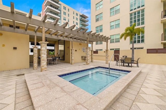 view of swimming pool with outdoor dining space, a hot tub, a pergola, and a patio