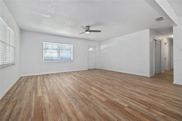 unfurnished room featuring light wood finished floors, visible vents, baseboards, a textured ceiling, and a ceiling fan