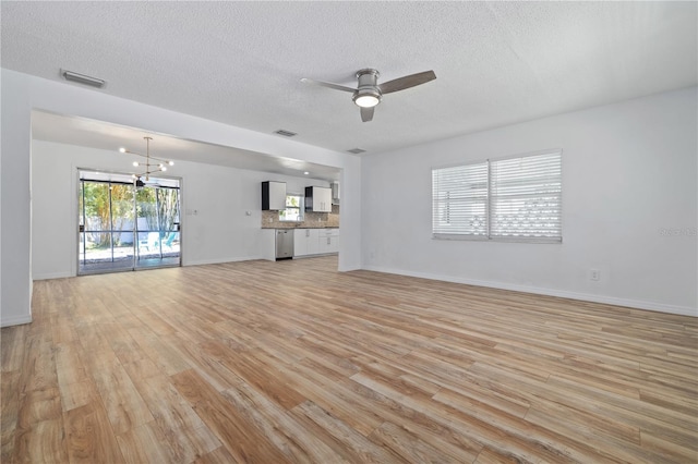 unfurnished living room with visible vents, baseboards, light wood-style floors, and ceiling fan with notable chandelier