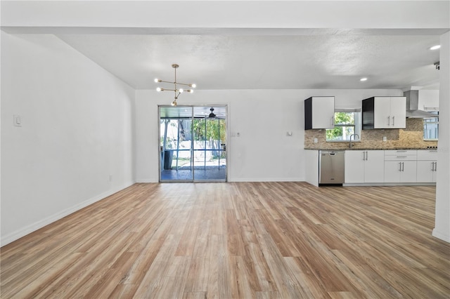 kitchen featuring tasteful backsplash, light wood-style flooring, wall chimney exhaust hood, and stainless steel dishwasher