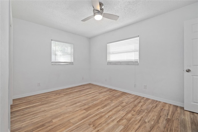 unfurnished room featuring a ceiling fan, light wood-style flooring, a healthy amount of sunlight, and a textured ceiling