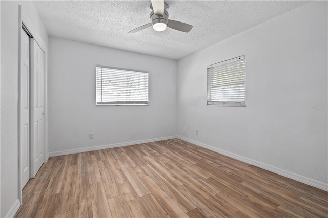 unfurnished bedroom with ceiling fan, baseboards, wood finished floors, a closet, and a textured ceiling