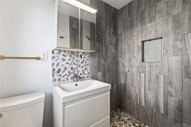 bathroom with tiled shower, toilet, and vanity