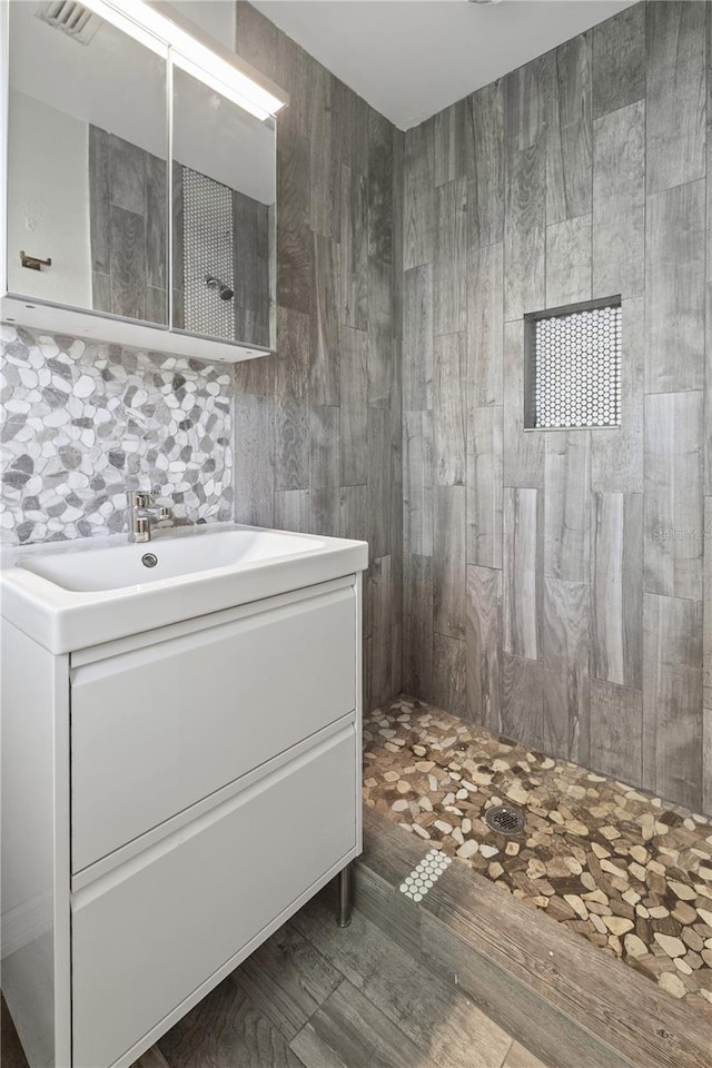 full bathroom featuring a tile shower, decorative backsplash, and vanity