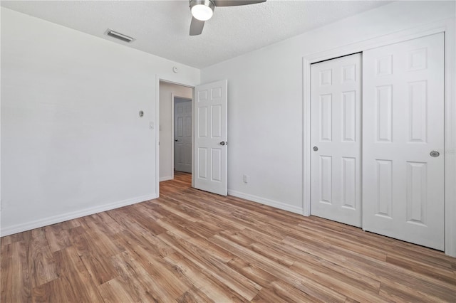 unfurnished bedroom with a ceiling fan, baseboards, visible vents, light wood finished floors, and a closet