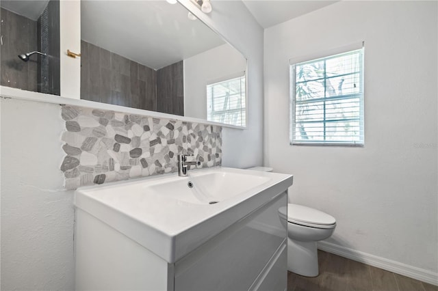 bathroom with toilet, tasteful backsplash, wood finished floors, baseboards, and vanity