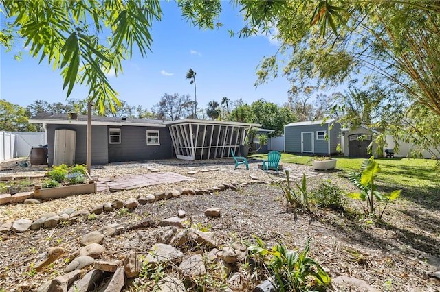 rear view of property with a patio, fence, a sunroom, an outdoor structure, and a storage shed