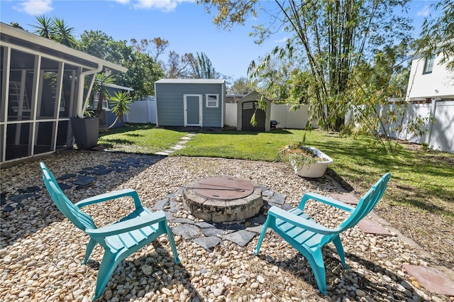 view of yard featuring an outbuilding, an outdoor fire pit, a fenced backyard, a sunroom, and a storage shed