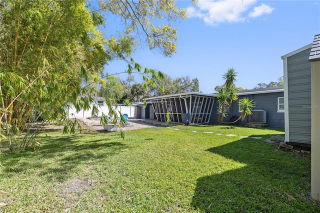 view of yard featuring central AC unit, a fenced backyard, and a sunroom