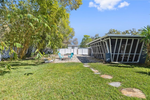 view of yard featuring a fenced backyard, a sunroom, and a fire pit