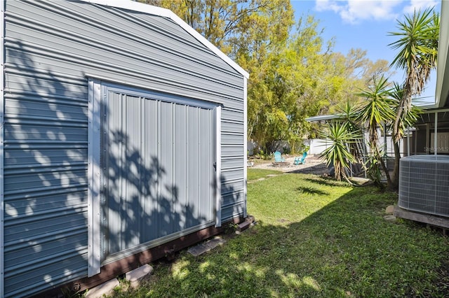 view of outdoor structure featuring an outbuilding, central AC unit, and fence