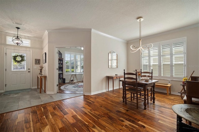 dining area with a notable chandelier, wood finished floors, crown molding, and a textured ceiling