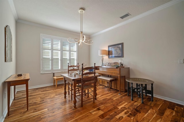 dining room with a chandelier, ornamental molding, baseboards, and wood finished floors