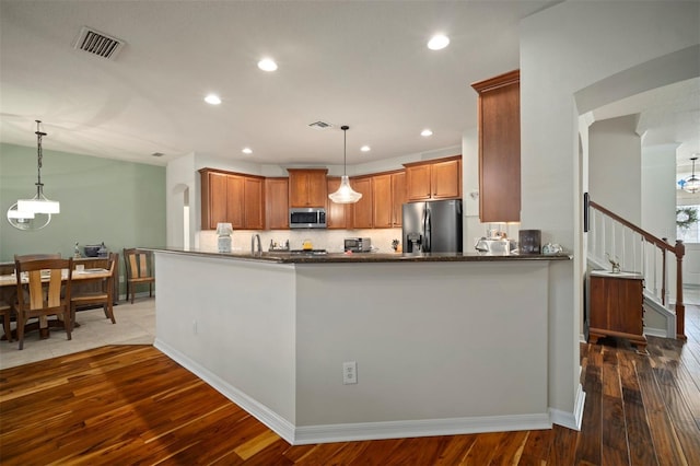 kitchen featuring visible vents, dark wood-type flooring, refrigerator with ice dispenser, stainless steel microwave, and recessed lighting