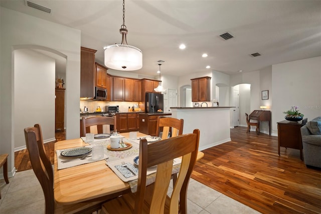 dining area with arched walkways, visible vents, and recessed lighting