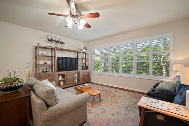 living area featuring wood finished floors, baseboards, and ceiling fan