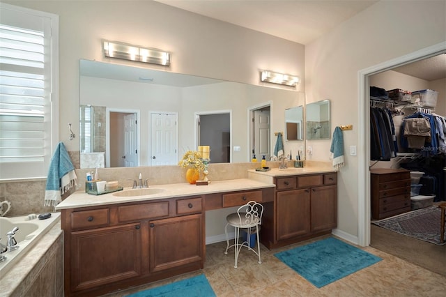 full bathroom with tile patterned floors, vanity, a walk in closet, and a garden tub