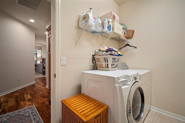 washroom with visible vents, washer and clothes dryer, wood finished floors, arched walkways, and laundry area