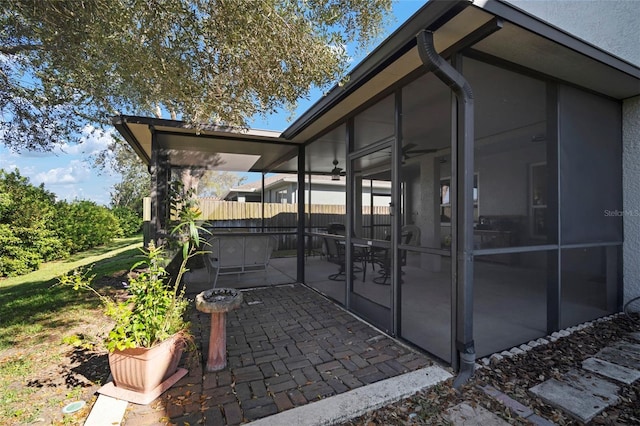 view of side of property featuring a patio, fence, and a sunroom