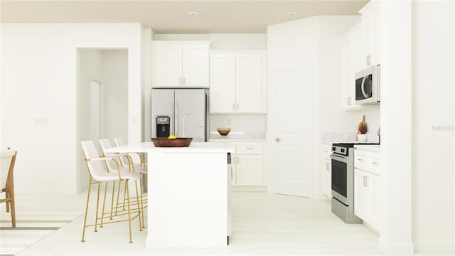 kitchen with a kitchen bar, white appliances, white cabinets, and a center island