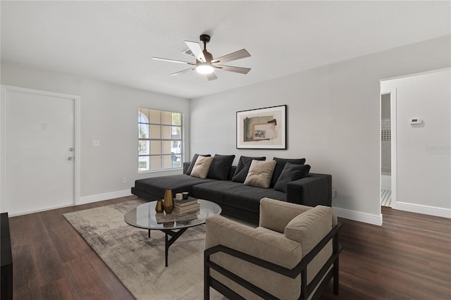 living room with ceiling fan, baseboards, and dark wood finished floors