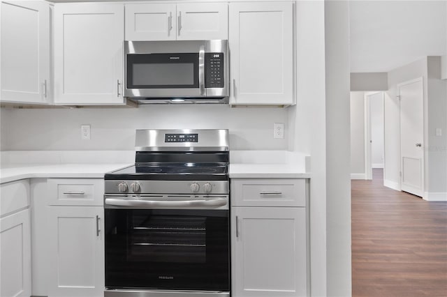 kitchen featuring white cabinetry, light countertops, wood finished floors, and appliances with stainless steel finishes