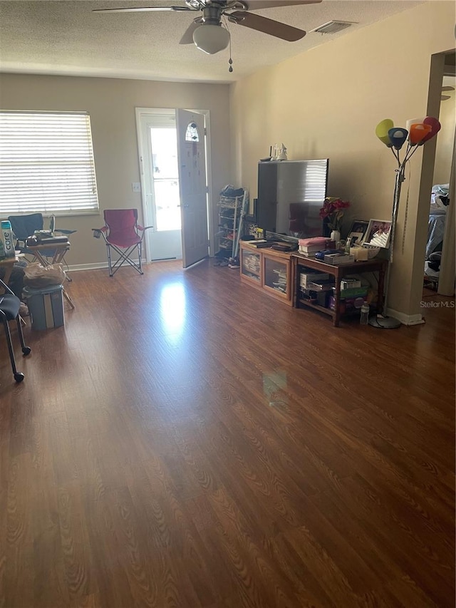 living room with visible vents, a textured ceiling, wood finished floors, and a ceiling fan