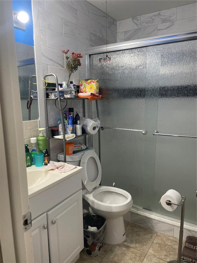 full bath featuring toilet, a stall shower, vanity, and tile walls