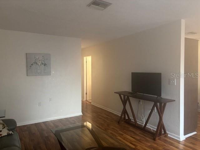 living room with visible vents, baseboards, and wood finished floors