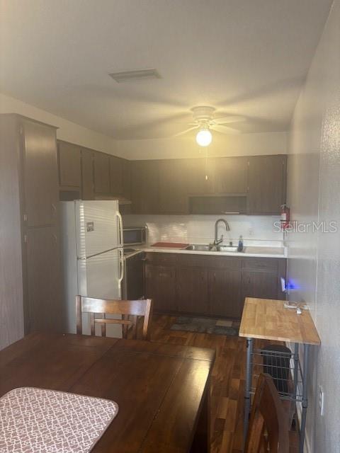 kitchen with visible vents, dark wood finished floors, light countertops, freestanding refrigerator, and a sink