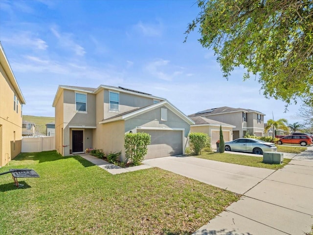 traditional-style home featuring fence, solar panels, stucco siding, a front lawn, and concrete driveway