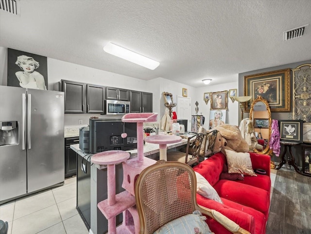 kitchen featuring light tile patterned floors, visible vents, appliances with stainless steel finishes, and a textured ceiling